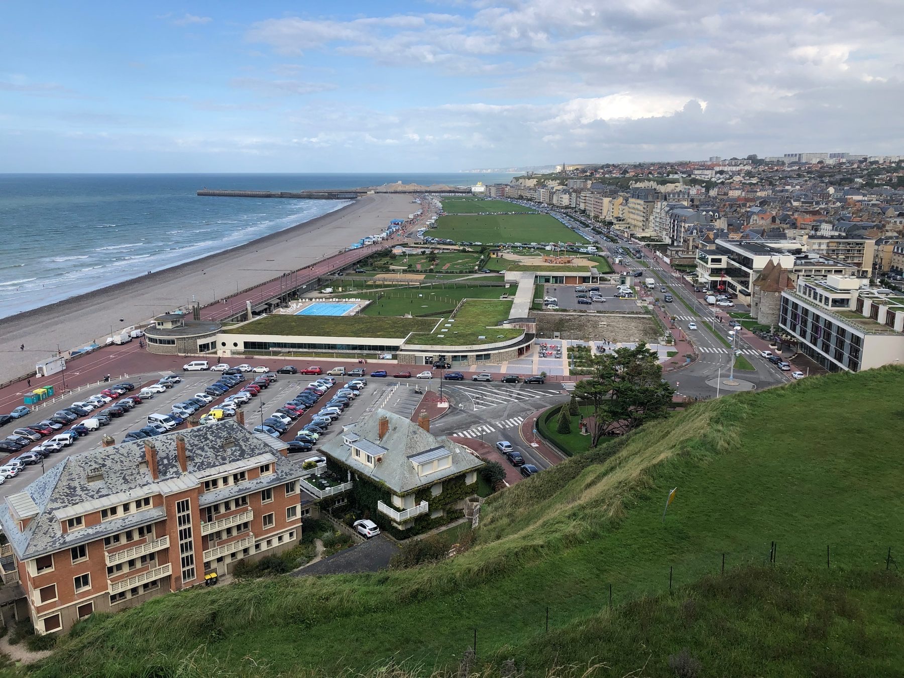 The shingle beach, seafront lawns and town of Dieppe seen from the clifftop above the promenade
