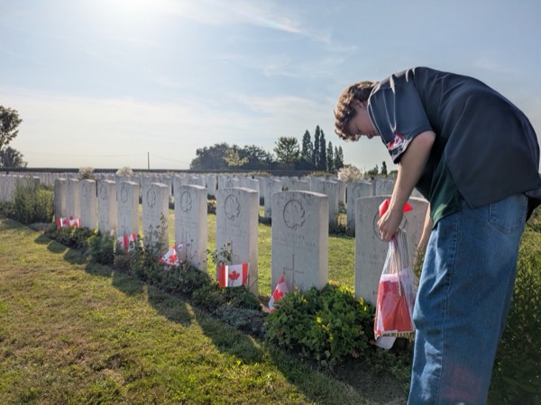 A guest placing a Canadian flag at a war grave in a Commonwealth cemetery
