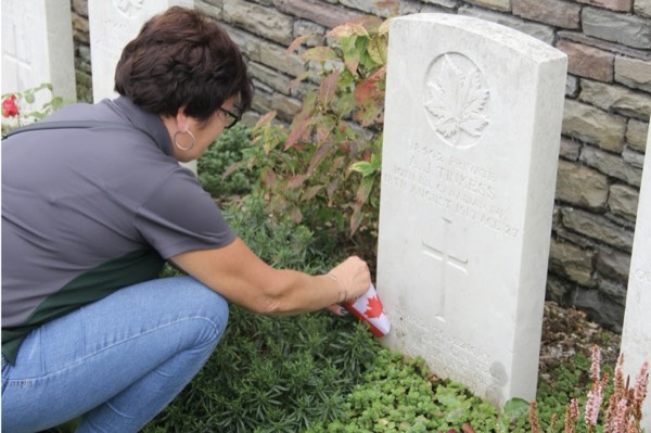 A guest placing a Canadian flag at a war grave